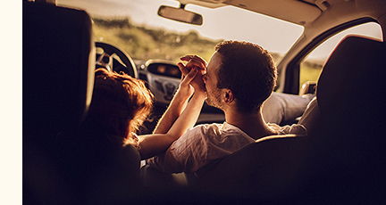 사진: 차 안에 앉은 남녀가 서로의 손을 잡고 있으며 남성이 여성의 손 등에 입맞춤을 하고 있는 사진