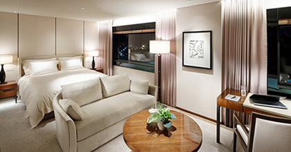 비즈니스 디럭스 룸의 객실 전경으로 왼편에는 침대가 놓여 있으며, 침대 앞에는 2인용 소파와 꽃이 올려진 낮은 테이블이 있다. 