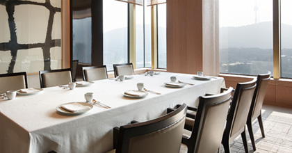 首尔新罗酒店韩餐厅罗宴的全景。 中间是通道，两旁排列着餐桌和椅子。