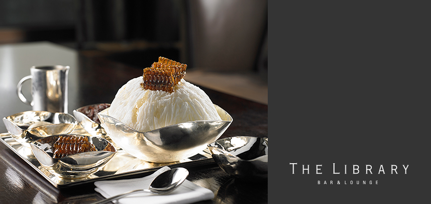 This is an image of The Library’s Honeycomb Affogato Bingsu. There are pieces of honeycomb on top of the bowl of delicate ice flakes.