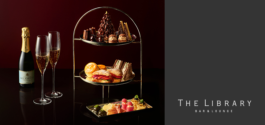 From the left to the right, there is a Champagne bottle with two glasses of Champagne and a royal tea set, savories and jams.