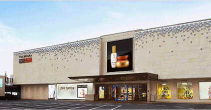 A panorama image of The Shilla Duty Free with the main entrance in the middle of the picture and a parking lot in front of it. 