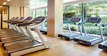 Running machines are placed side by side, looking at a glass window with photos of the indoor gymnasium.