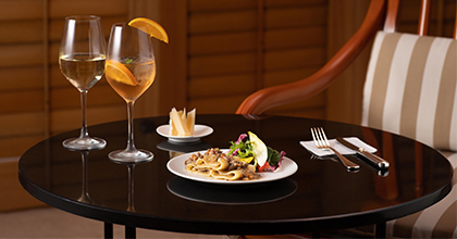 테이블 위에 포크와 나이프, 와인잔과 음식이 놓여져 있는 이미지