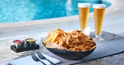 야외수영장 테이블 위 치킨과 포테이토, 생맥주 두잔이 놓여진 이미지