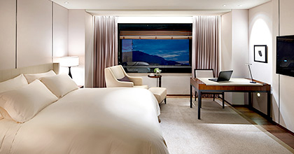 디럭스 더블룸 객실 전경으로, 침대와 데스크가 놓여있다.