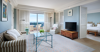 파스텔 톤의 인테리어에 3인 소파와 테이블 텔레비전이 놓여져 있는 바다가 보이는 거실의 수페리어 스위트 이미지