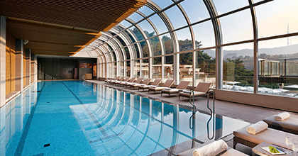 유리돔을 통해 햇살이 들어오고 있는 실내 수영장 이미지