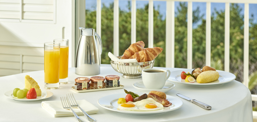 Image of a room service breakfast on a table with an omelet, bread, coffee, orange juice, and fruit.