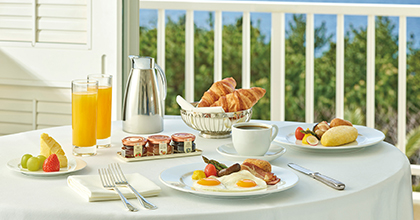 Image of room service breakfast on a table with an omelet, bread, coffee, orange juice, and fruit.
