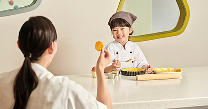 어린이가 셰프 옷을 입고 쿠킹 프로그램에 참여하고 있는 이미지