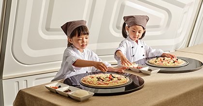 어린이 2명이 셰프 복장을 하고 콤비네이션 피자를 만들고 있는 이미지
