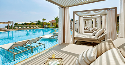 수영장 앞에 소파 형태의 쁘띠 카바나가 놓여진 이미지