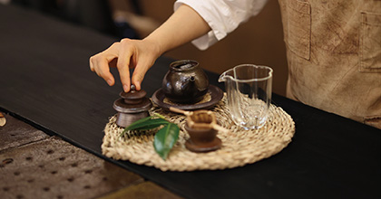 앞치마를 입은 사람이 다구를 만지고 있는 이미지