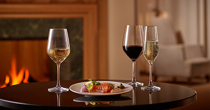 와인 두 병과 초콜릿, 과자, 치즈 등 간식들이 초 장식과 함께 진열되어 있는 이미지