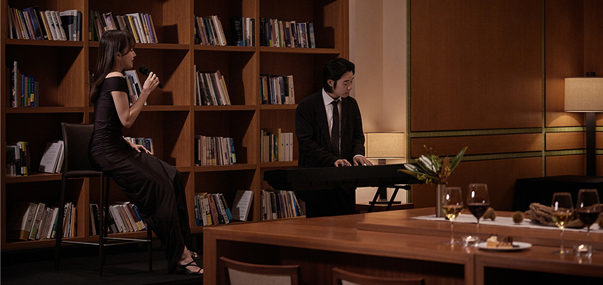 여성 두 명이 드레스를 입고 피아노 연주와 노래를 부르고 있는 이미지